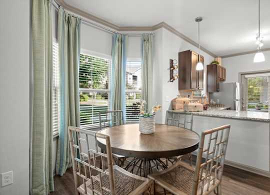 a dining room with a table and chairs and a kitchen in the background at Stonepost Crossing Apartments, Overland Park, KS, 66213