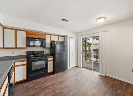 an empty kitchen with black appliances and a sliding glass door at Deerfield Apartments, Olathe, Kansas, 66062