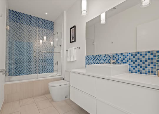 a bathroom with white cabinets and blue and white tile