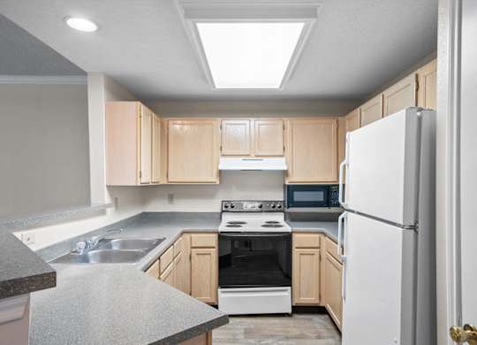 A kitchen with a white refrigerator, sink, and stove.at The Claremont Apartment Homes, Overland Park, 66210