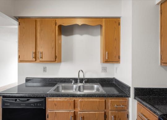 a kitchen with a sink and counters and wooden cabinetsat Deerfield Apartments, Olathe, KS, 66062