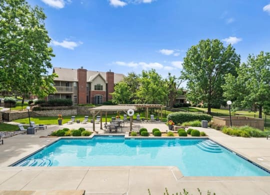 a swimming pool with trees and a building in the background at Highland Park Apartment Homes, Overland Park, KS, 66214
