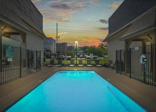 A swimming pool surrounded by a fence and buildings. at Malvern Hill Apartment Homes, 66103, Kansas