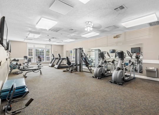 a large fitness room with cardio equipment and a large windowat Stonebriar Apartments, Kansas