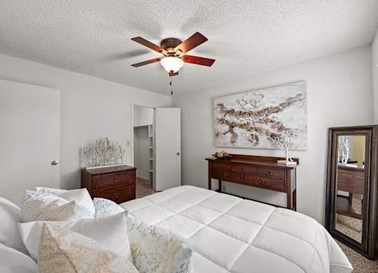 A bedroom with a large bed and a ceiling fan.