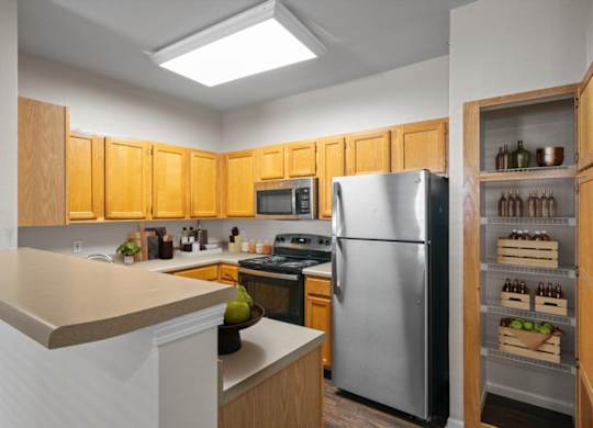 A kitchen with wooden cabinets and a stainless steel refrigerator. at Somerset Oaks Apartment Homes, Olathe