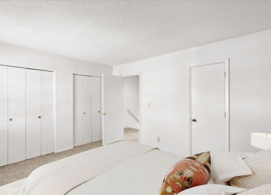 a white bedroom with a large bed and white closets