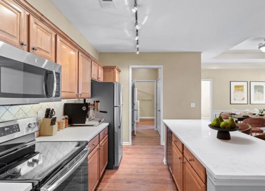 A kitchen with stainless steel appliances, hardwood floors, stone backsplash, quartz countertops and a kitchen island at Avignon Apartments in Olathe, Kansas