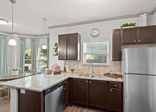a kitchen with brown cabinets and a granite counter top at Stonepost Crossing Apartments, Kansas, 66213