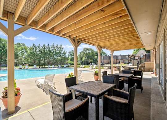 A patio with a table and chairs overlooking a pool.