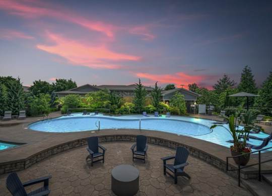 A beautiful outdoor swimming pool area with lounge chairs and a hot tub.