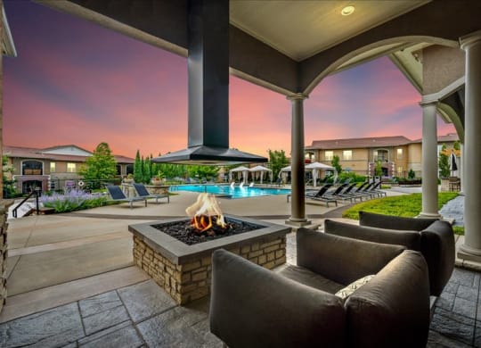 a patio with a fire pit and chairs and a pool