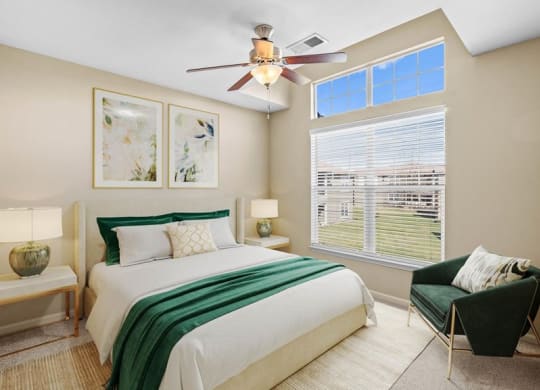 A bedroom with a ceiling fan and a large window with natural lighting