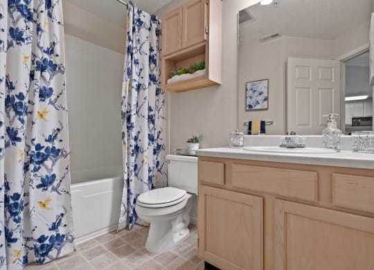a bathroom with a white toilet next to a bathtub with a blue and white shower curtain  at Claremont, Kansas, 66210