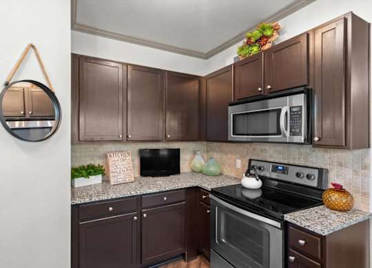 a kitchen with dark cabinets and stainless steel appliances at Stonepost Crossing Apartments, Overland Park, Kansas