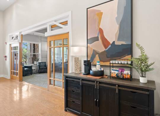 A painting hangs on the wall above a black cabinet in a room with a wooden floor. at Stonepost Lakeside Apartment Homes, Olathe, Kansas