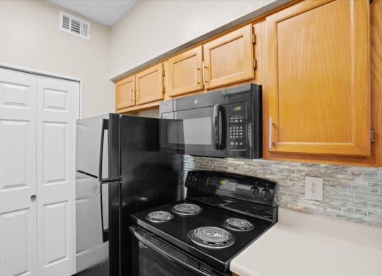 a kitchen with a stove top oven next to a refrigerator at Creekview Apartment Homes, Texas