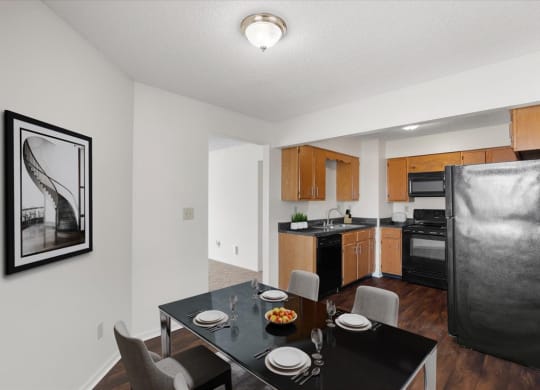 a kitchen and dining room with a black table and chairs at Deerfield Apartments, Olathe, Kansas, 66062