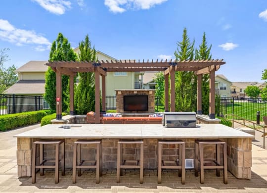 a large outdoor kitchen with a bar and a fireplace