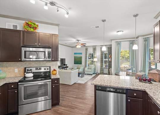 a kitchen and living room with wood floors and a ceiling fan at Stonepost Crossing Apartments, Overland Park, 66213