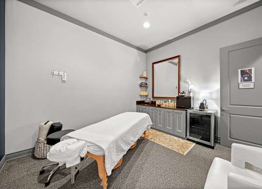 A room with a massage table and a mirror on the wall.