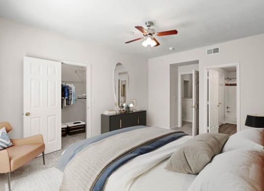 A bedroom with a ceiling fan, large walk in closet, and an attached master bathroom.