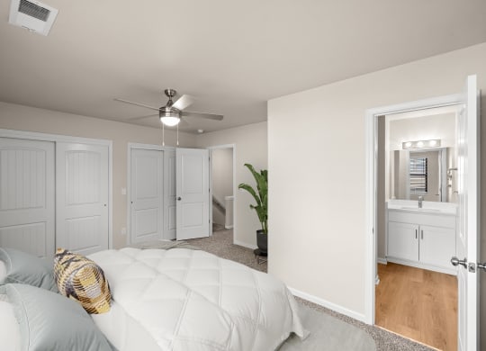 a bedroom with a white bed and a ceiling fan