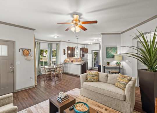 a living room with a couch a table and a ceiling fan at Stonepost Crossing Apartments, Overland Park