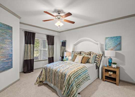a bedroom with a bed and a ceiling fan at Stonepost Crossing Apartments, Overland Park, KS