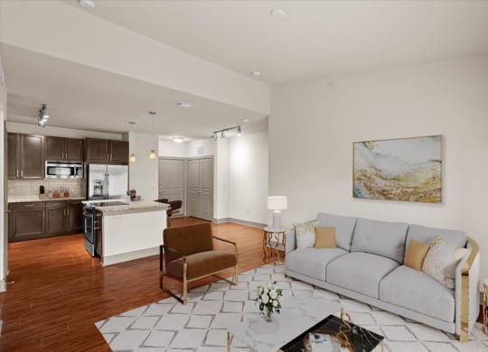 a living room with a couch and a chair in front of a kitchen with a stove and