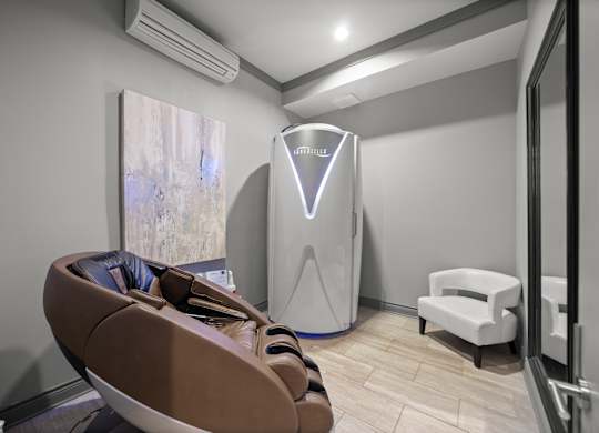 A room with a brown chair and a white cabinet.
