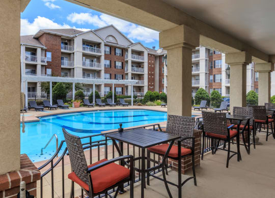 A poolside dining area with tables and cushioned chairs.