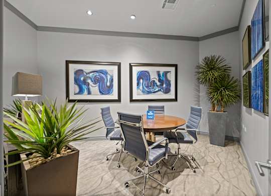 A conference room with a table, chairs, and two framed artworks on the wall.