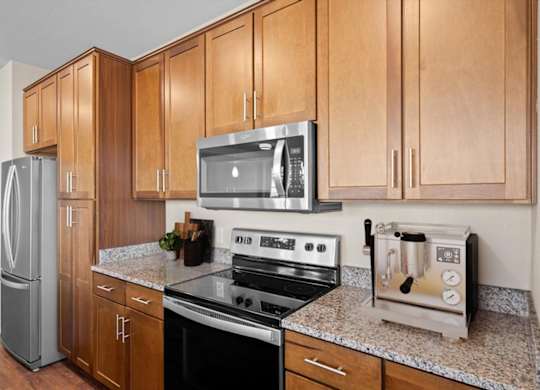 a kitchen with a stove top oven next to a refrigerator at The Dorset, Kansas City, 64112
