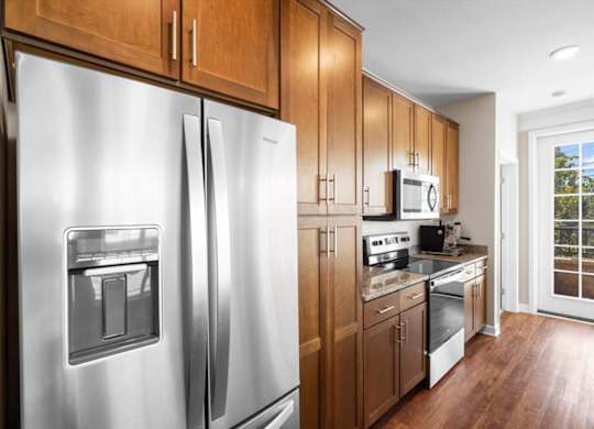 a kitchen with wooden cabinets and stainless steel appliances at The Dorset, Kansas City, 64112