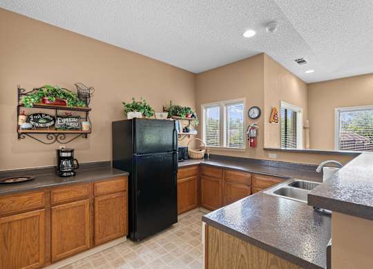 A kitchen with a black refrigerator and wooden cabinets.