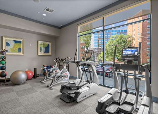A gym with a row of treadmilers and exercise balls.