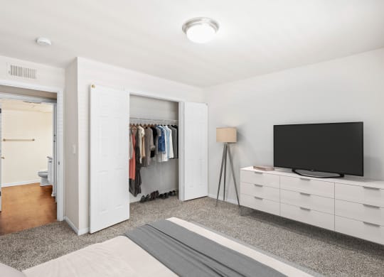a bedroom with a bed and a dresser with a tv on top of itat Stonebriar Woods Apartments, Overland Park, 66213