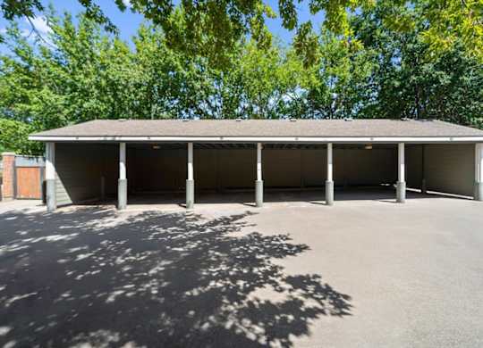 A large building with a grey roof and pillars is surrounded by trees. at Somerset Oaks Apartment Homes, Olathe 66062