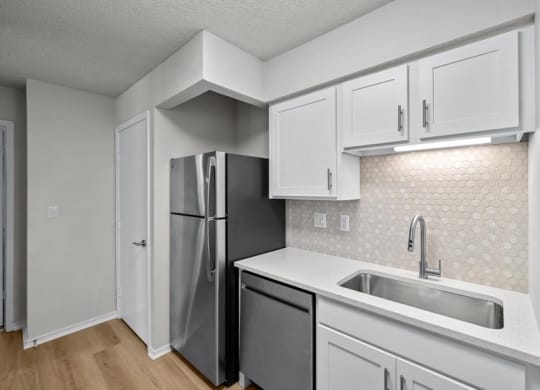 a kitchen with white cabinets and a stainless steel refrigerator at Highland Park Apartment Homes, Overland Park