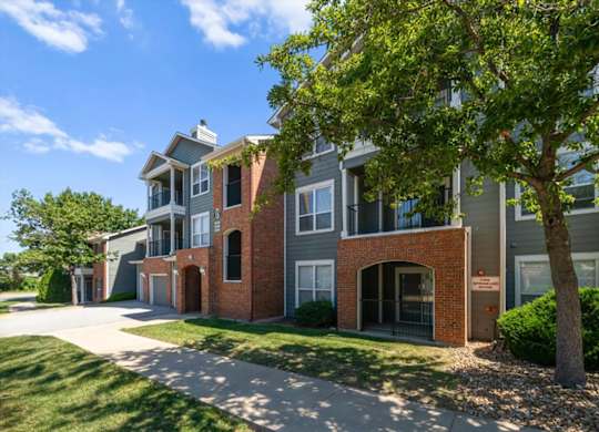 A tree is in front of a building. at Somerset Oaks Apartment Homes, Olathe