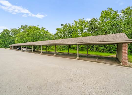 A long covered parking area with a brick pillar.