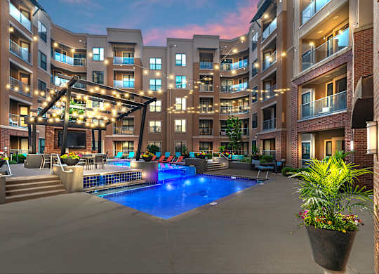 A large outdoor pool area with a hot tub and lounge chairs at a residential building.