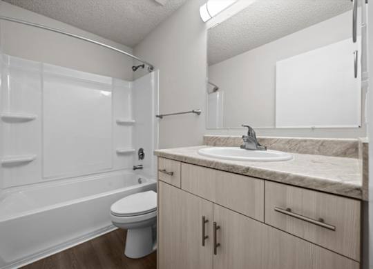 A white bathroom with a toilet, sink, and shower.