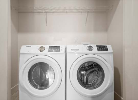 Included front-loading washer & dryer inside a laundry room with a wire rack shelf at The Mirabelle Luxury Apartments on the Plaza in Kansas City.