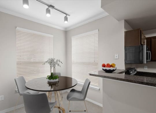 a dining area with a table and chairs and a kitchen in the background at The Clairborne Apartment Homes, Grand Prairie, TX