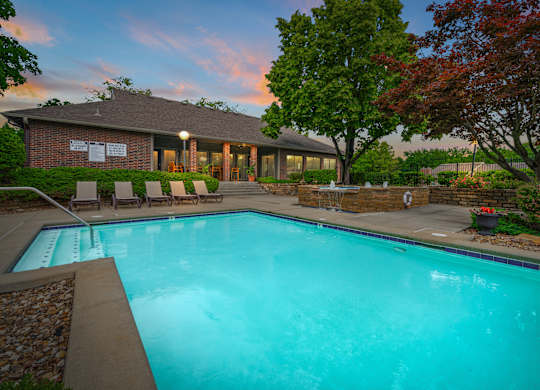 A swimming pool in front of a house with trees around.