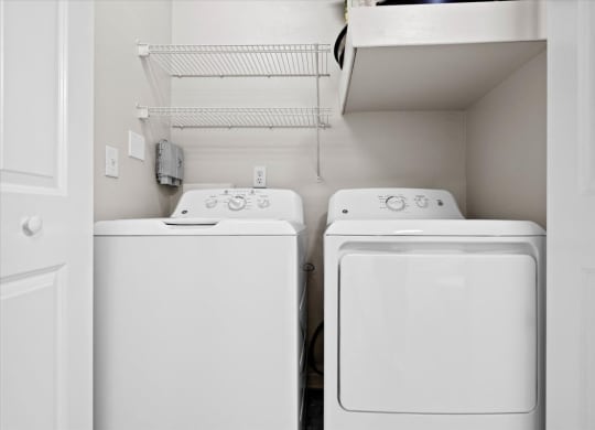 White washer & dryer included in a laundry room with wire rack shelves.