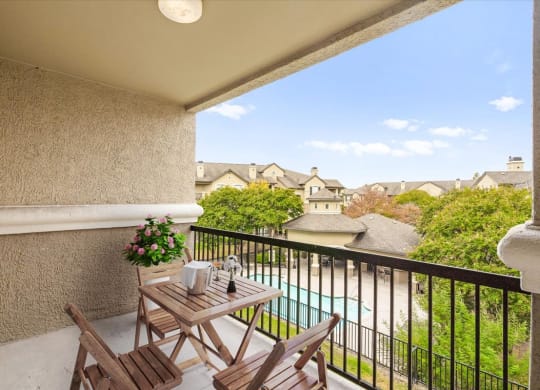 a balcony with a table and chairs and a pool in the background