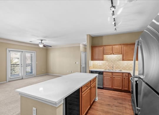 A kitchen with quartz countertops, stainless steel appliances, stone backsplash, and plank flooring at Avignon Apartments in Olathe, Kansas